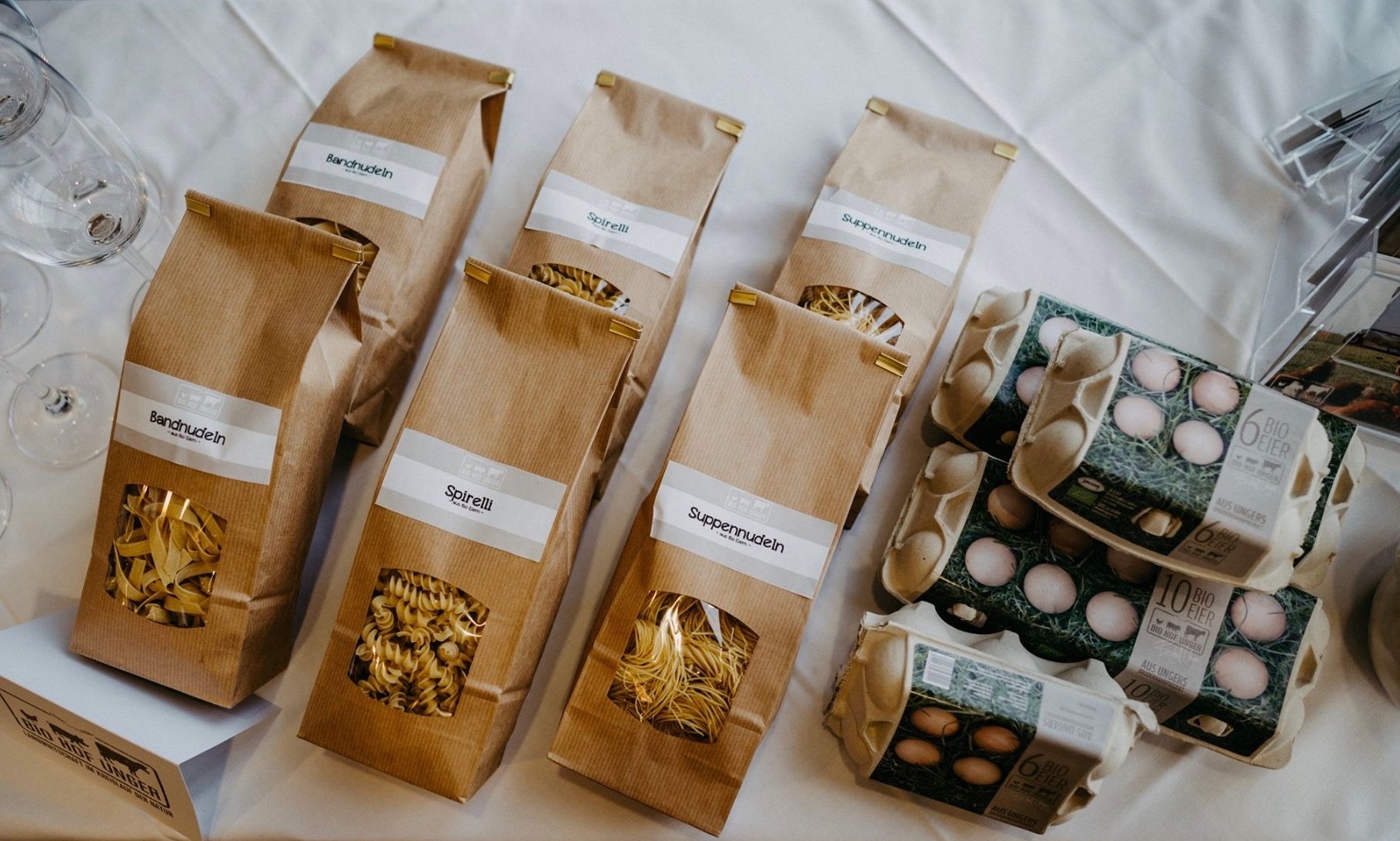 A Biohof Unger termékei: tészták barna zacskókban és tojásos dobozok egy asztalon.