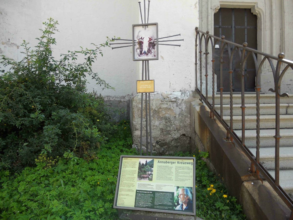 Az Annabergi keresztútról szóló tájékoztató tábla egy lépcső és növények mellett.