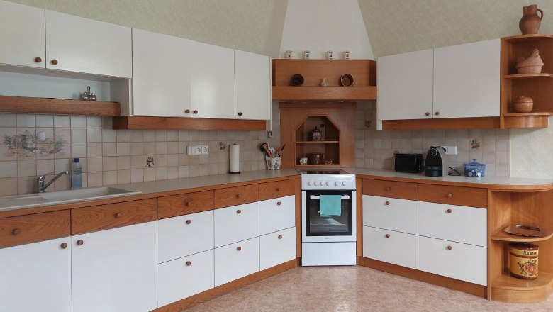 Konyha feh&eacute;r &eacute;s fa sz&iacute;nű szekr&eacute;nyekkel, tűzhely &eacute;s mosogat&oacute;.