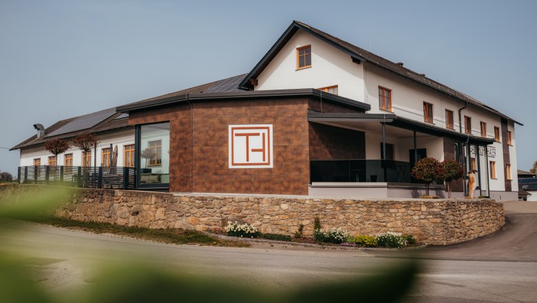 A "Gasthof Thaler" feliratú modern épületet kőfal és növények veszik körül.