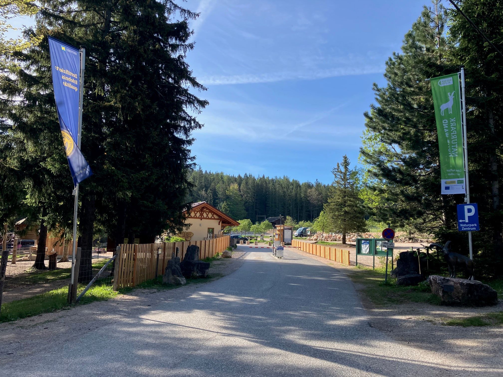 Natúrpark központ bejárata zászlókkal és fákkal.
