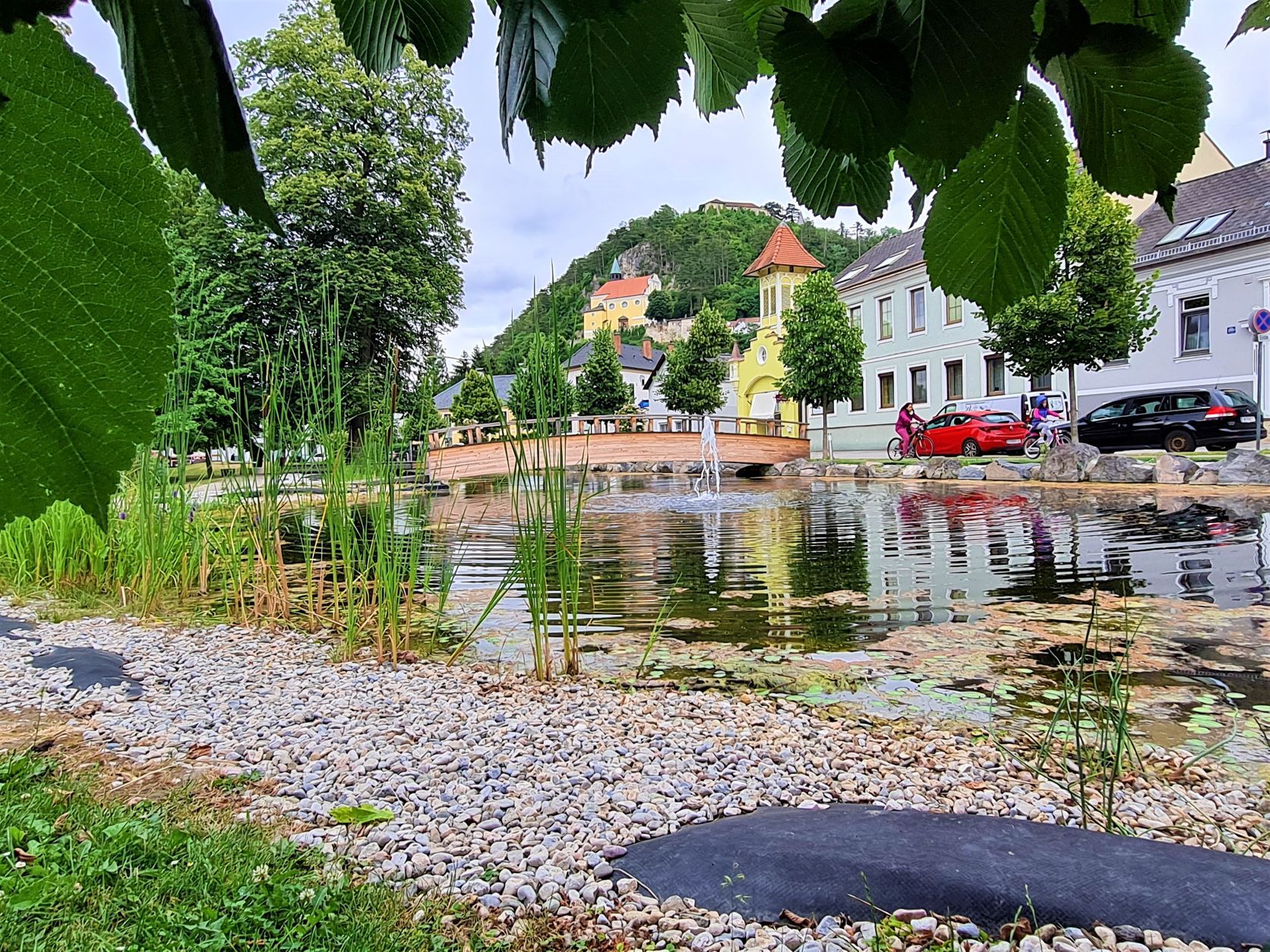 Kilátás a pitteni hegyi templomra egy parkból egy tóval és egy híddal