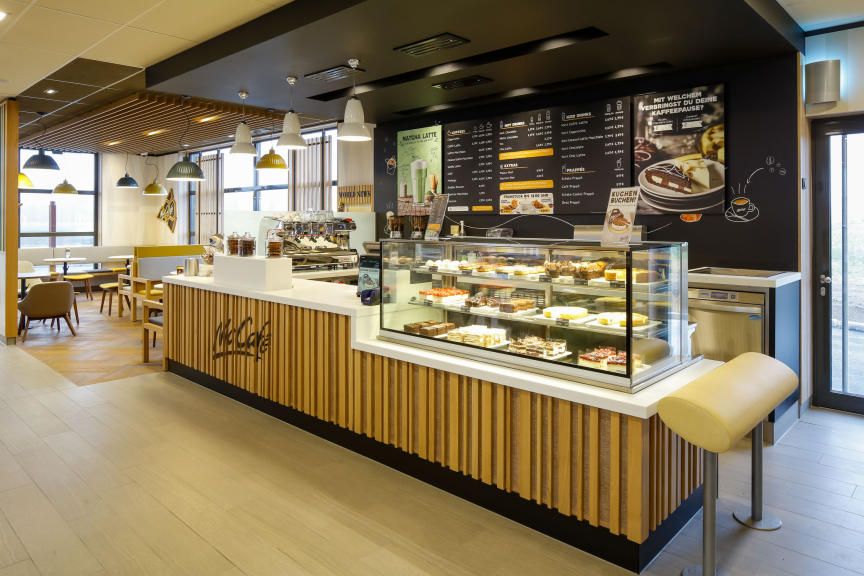 Egy McCafé belső nézete pultokkal és ülőhelyekkel.