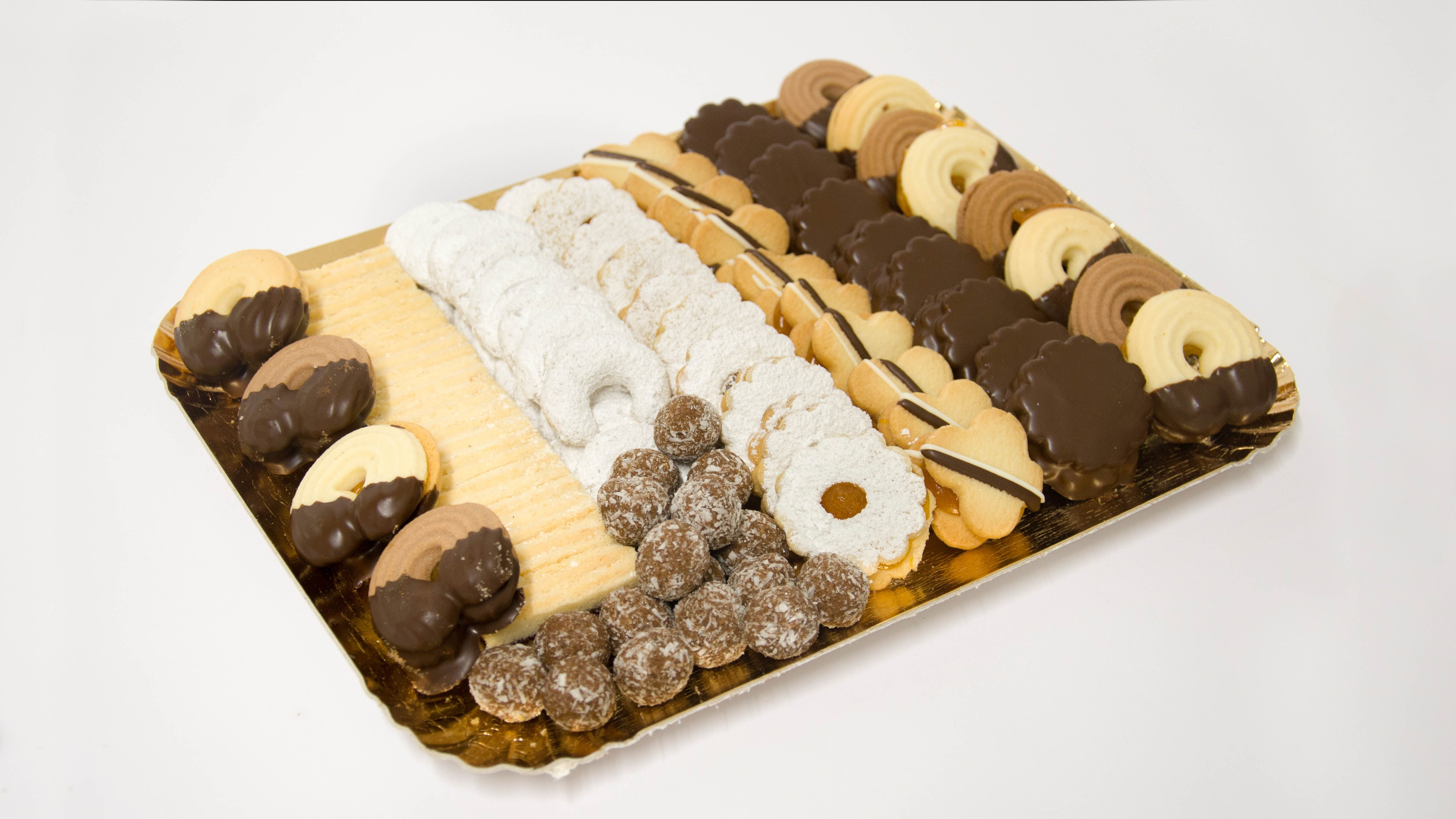 Különböző típusú teasütemények egy aranyszínű tálcán.