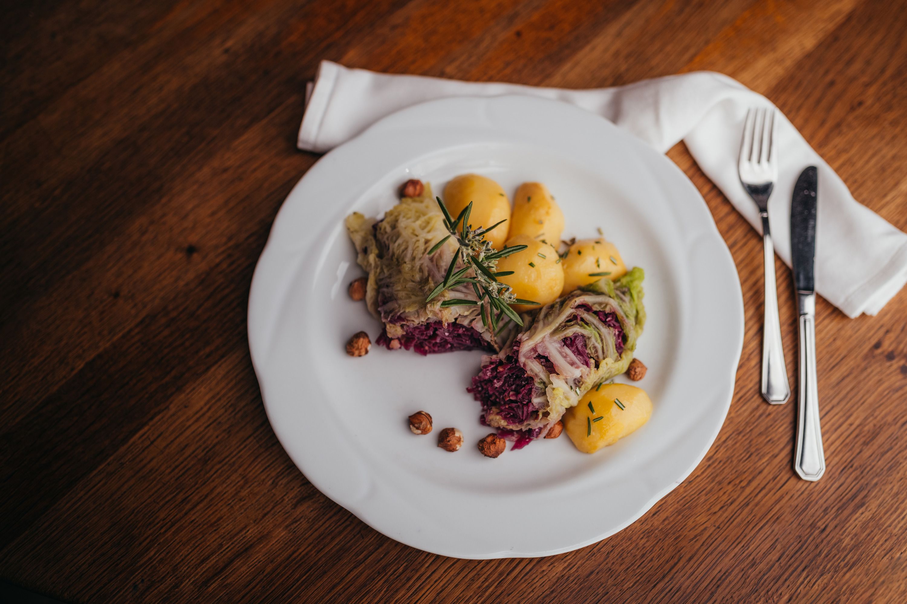 Egy tányér töltött káposztalevelekkel, burgonyával és dióval, rozmaringgal díszítve.