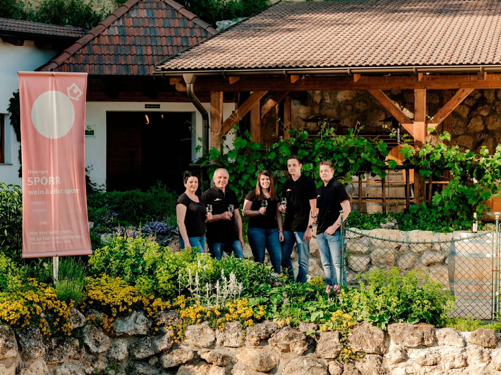 Ötfős csoport egy pincészet előtt egy Sporr transzparenssel.