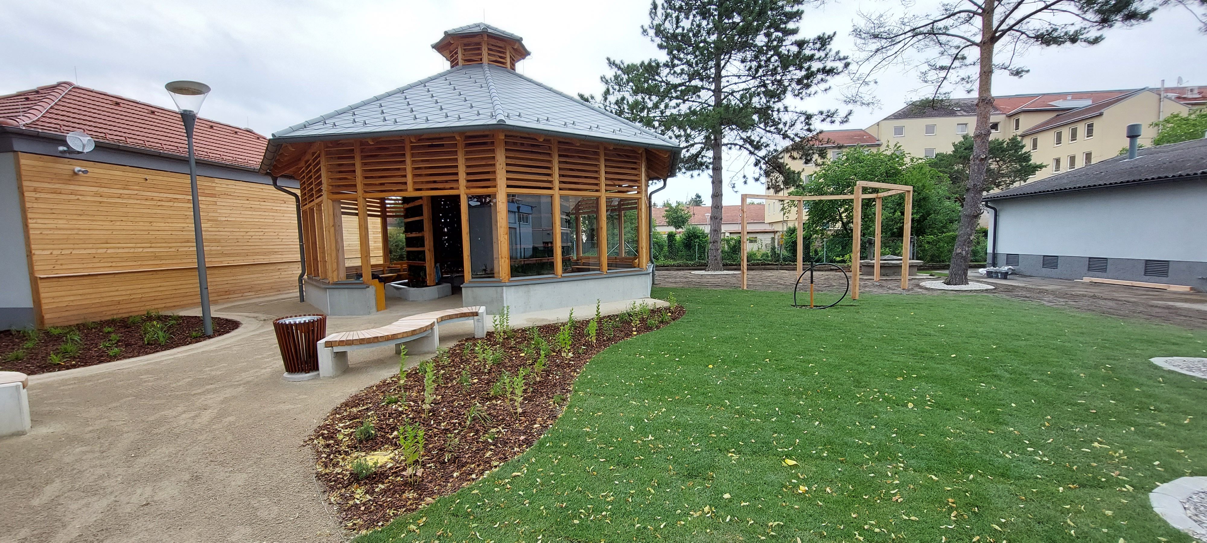 Modern inhalatórium, faépítésű, üvegablakokkal, gondozott kertben, pázsittal és fákkal.