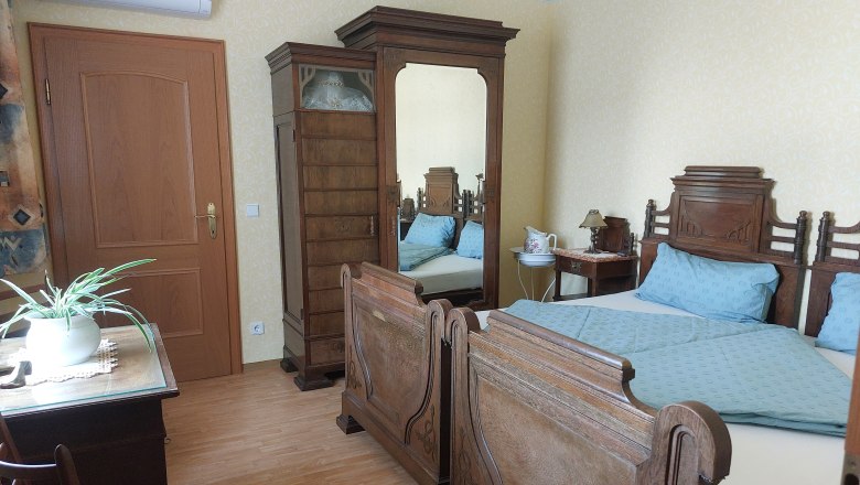 H&aacute;l&oacute;szoba antik fab&uacute;torokkal, francia&aacute;ggyal, t&uuml;kr&ouml;s szekr&eacute;nnyel, asztallal &eacute;s sz&eacute;kkel.