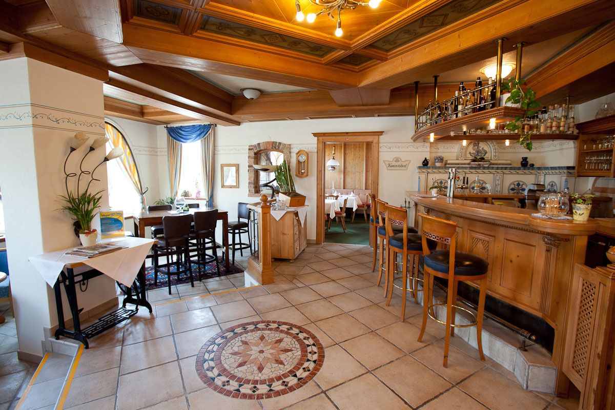 Hangulatos szállodai bár fából készült bútorokkal és dekoratív csempézett padlóval.