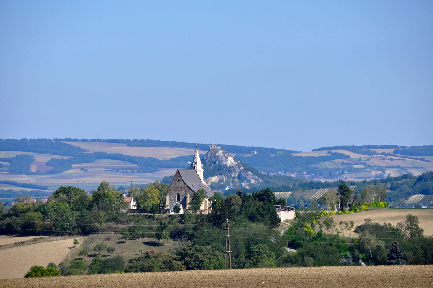 Tájkép templommal és dombdal a háttérben.