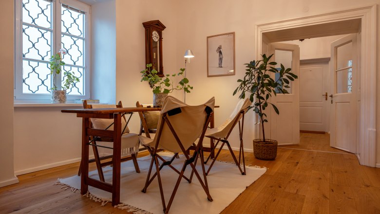 Hangulatos szoba fapadl&oacute;val, asztallal, sz&eacute;kekkel &eacute;s n&ouml;v&eacute;nyekkel.