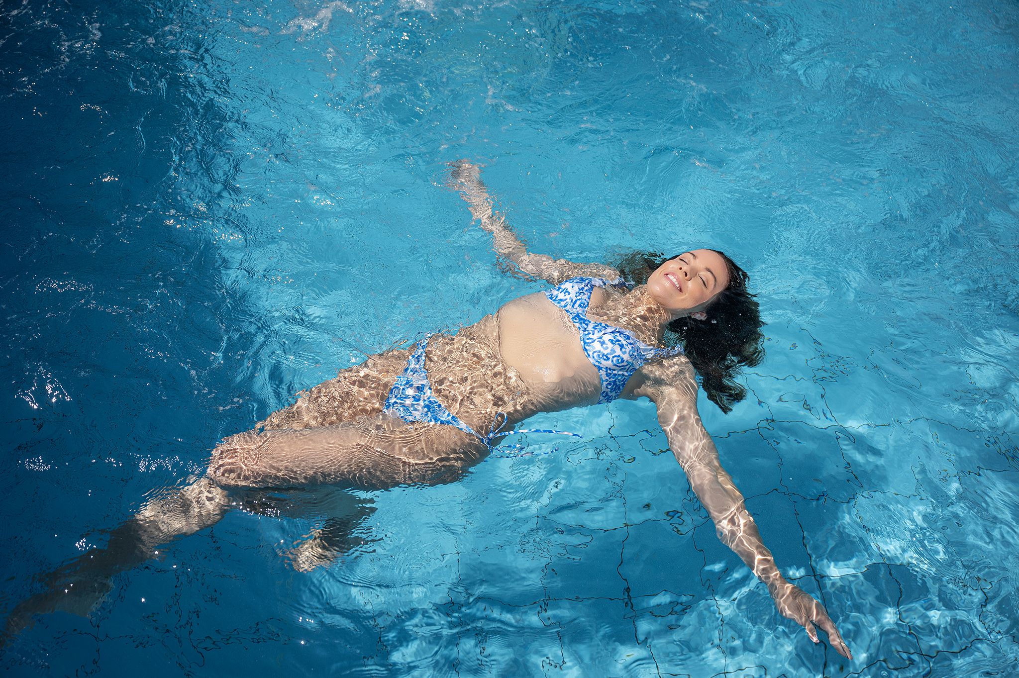 Kék bikinis nő lebeg a medencében.