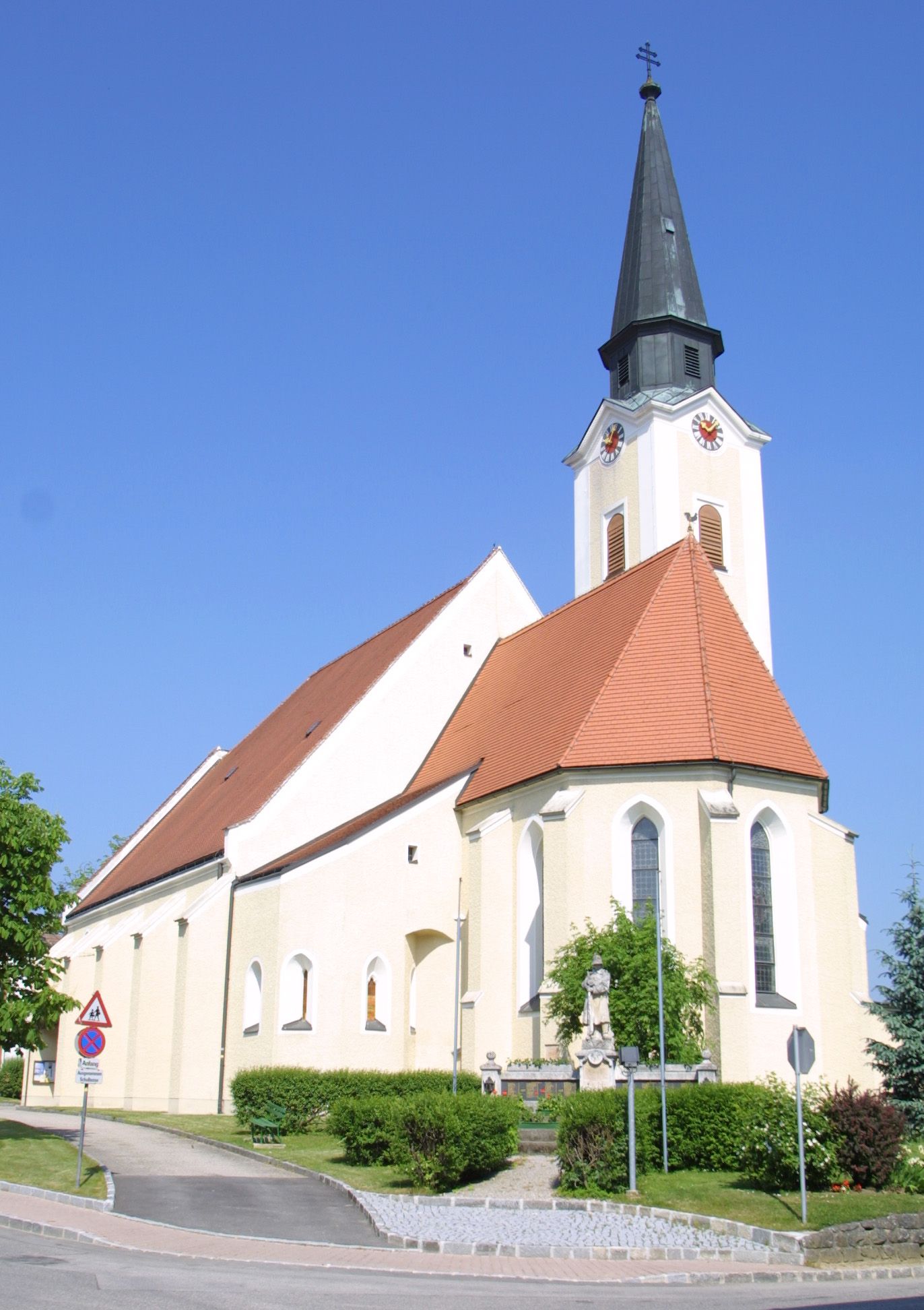 Hürmi templom csúcsos toronnyal és vörös tetővel a kék égbolton.