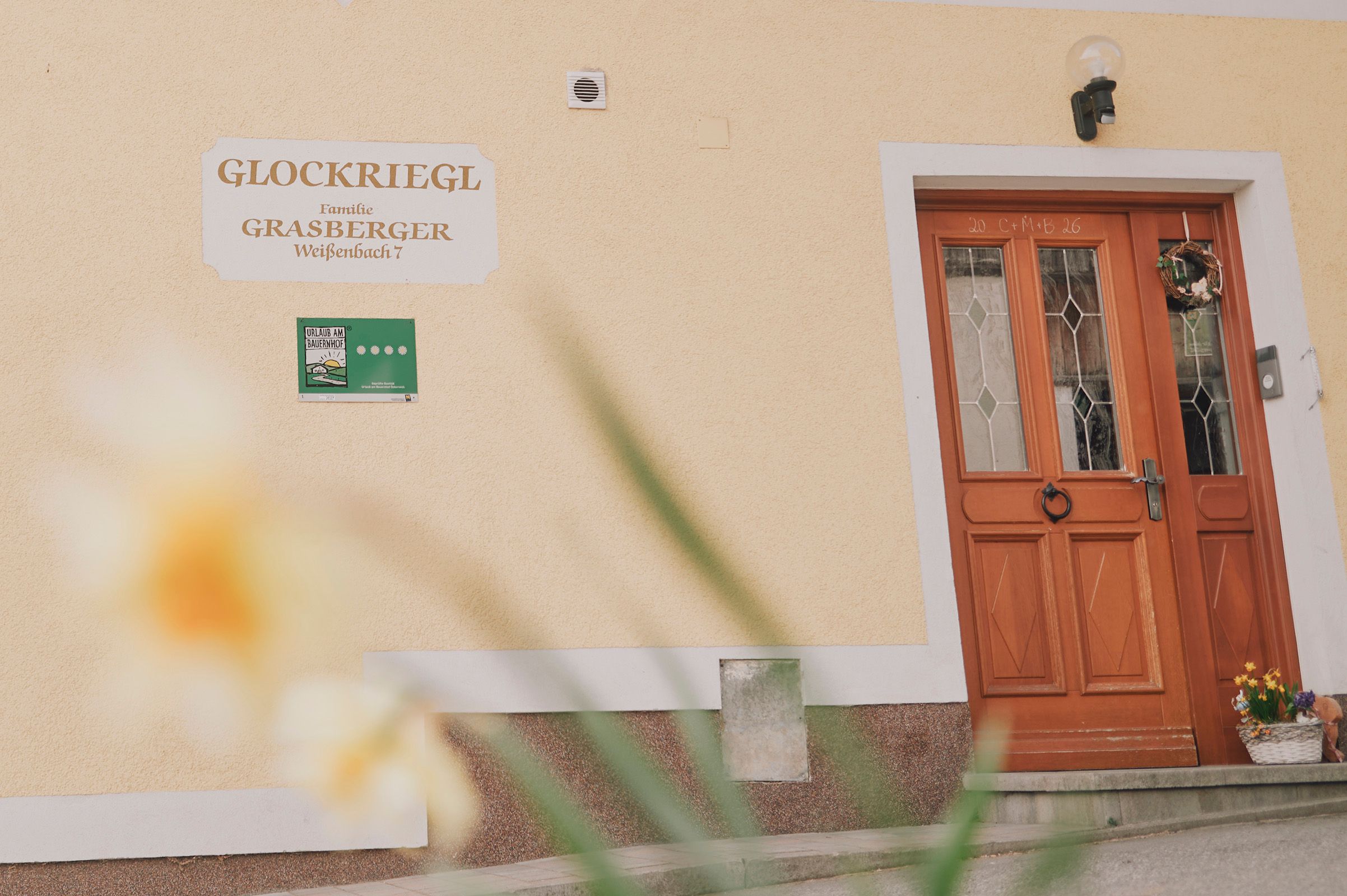 Egy ház bejárata faajtóval és "Glockriegl" felirattal a falon.