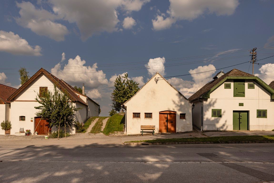 Három hagyományos pinceház Kettlasbrunnban, kék, felhős ég alatt.