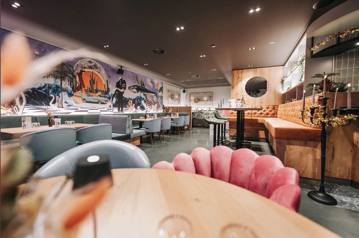 Egy stílusos étterem belső nézete, modern berendezéssel és faliképekkel.