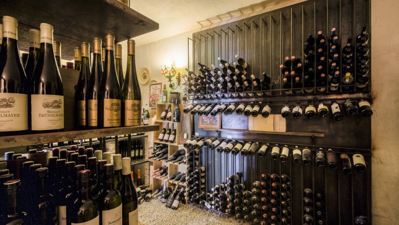 Egy borospince, a polcok tele vannak sz&eacute;pen egym&aacute;sra pakolt boros&uuml;vegekkel.