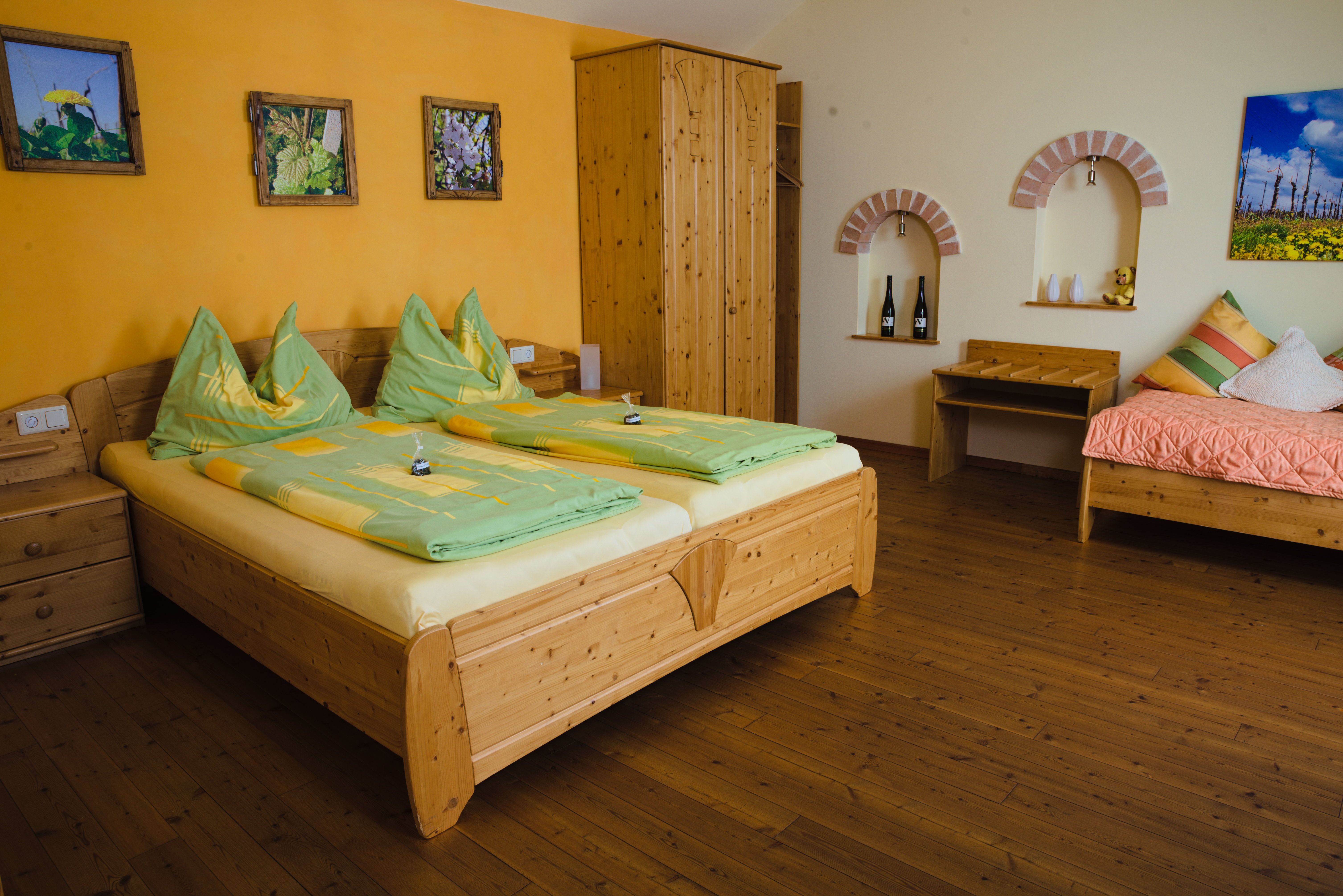 Hangulatos vendégszoba fabútorokkal, franciaággyal, egyszemélyes ággyal és dekoratív faliképekkel.