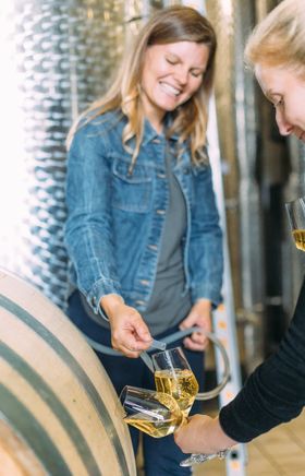 Inmitten der beeindruckenden Weinlandschaft wird frischer Wein aus dem Holzfass verkostet. Die fröhliche Atmosphäre und die strahlenden Gesichter der Winzerin und ihrer Gäste laden dazu ein, die Aromen des Mostviertels zu genießen.