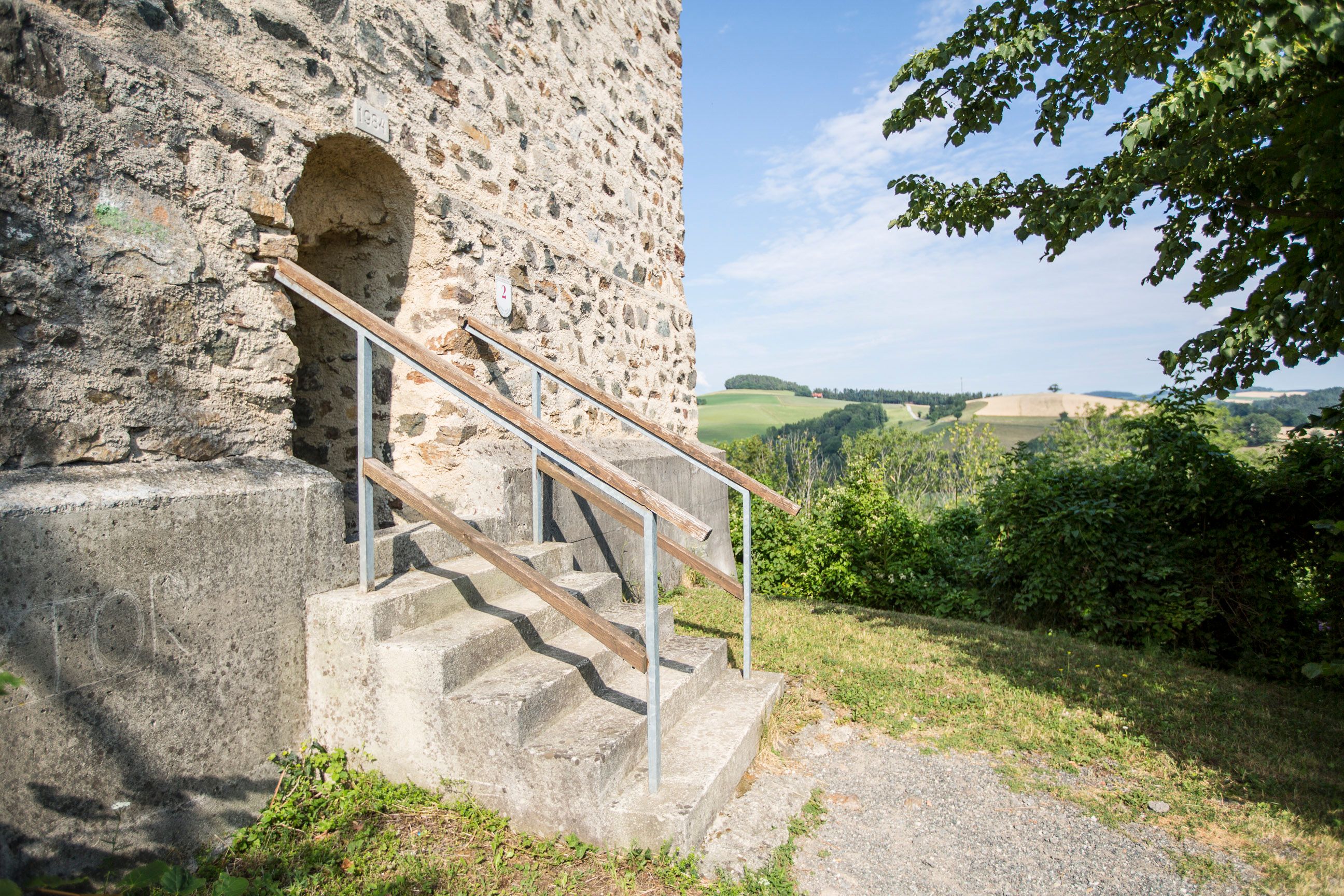 Bejárat a Kirchschlag-vár romjainak tűztornyához, háttérben lépcső és táj.