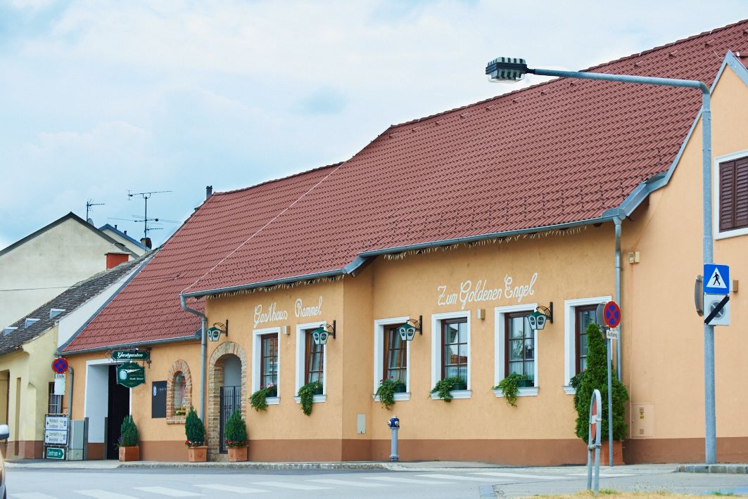 Hagyományos vendéglő sárga homlokzattal és piros tetővel, "Gasthaus Rammel" és "Zum Goldenen Engel" felirattal.