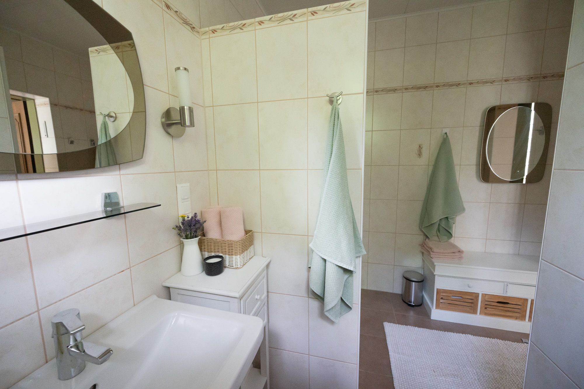 Modern fürdőszoba mosdóval, tükörrel, törölközőkkel és dekorációval.