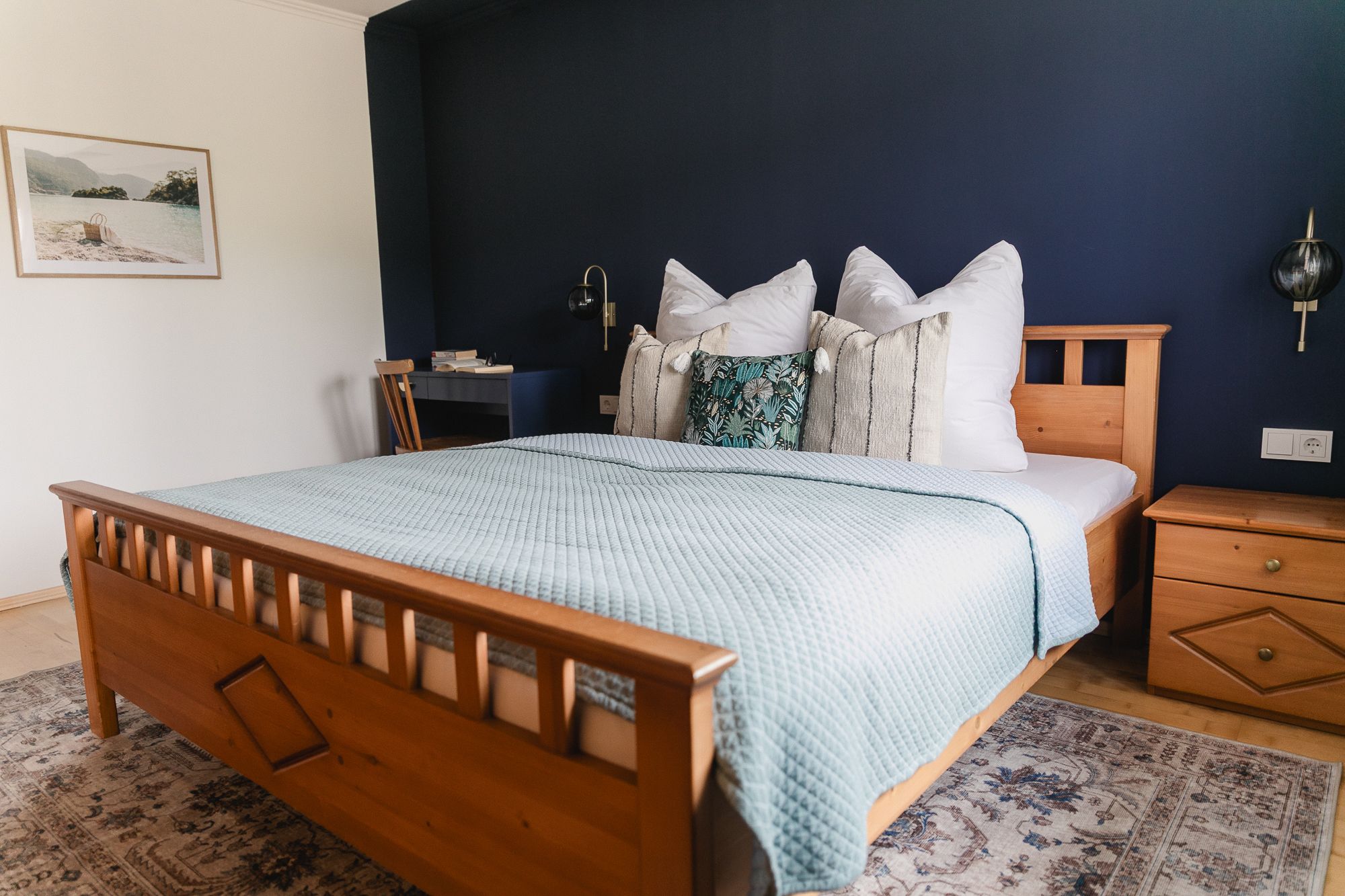 Hangulatos hálószoba faággyal, kék fallal és díszpárnákkal.