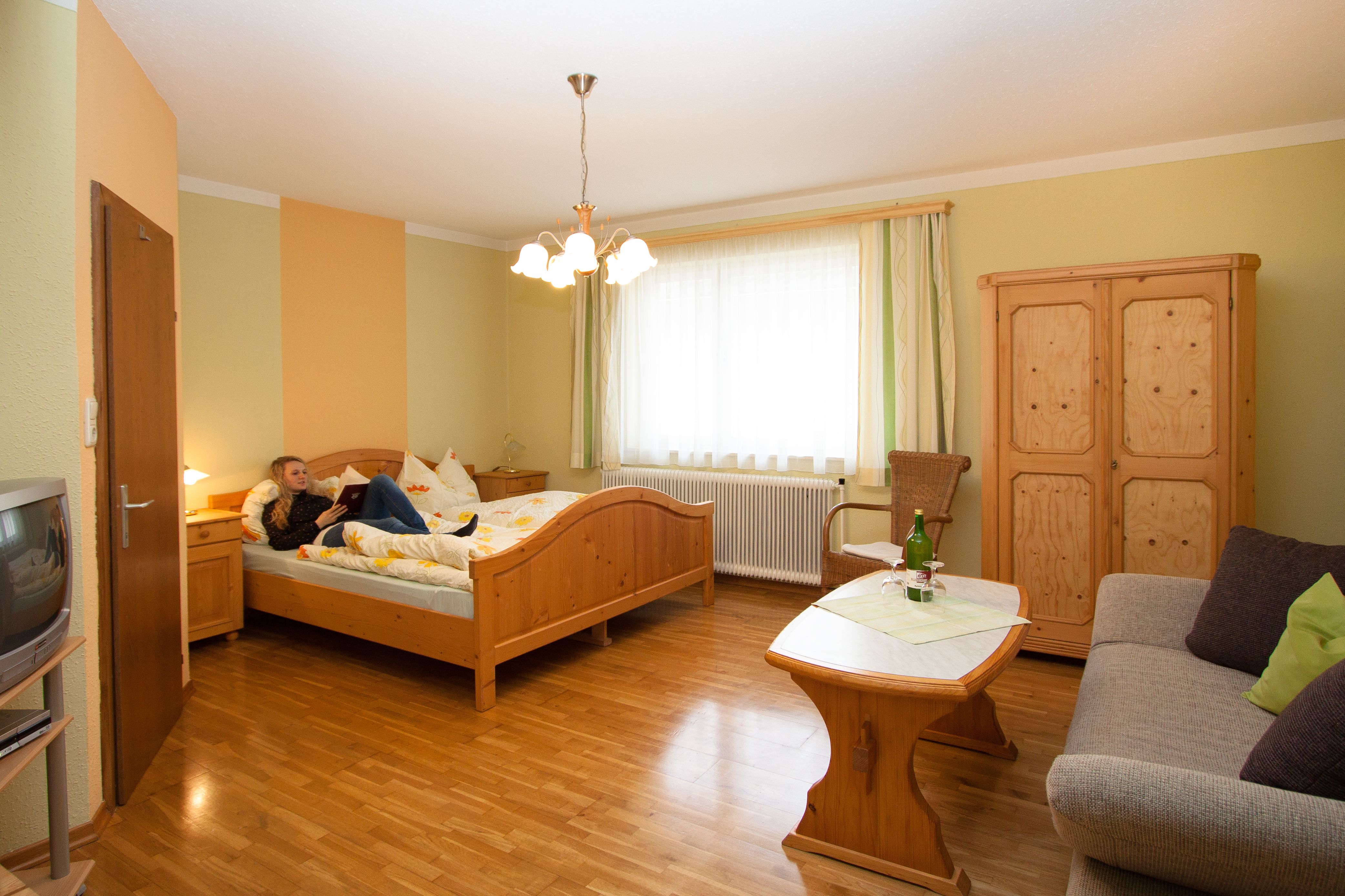 Hangulatos hotelszoba fabútorokkal, ággyal, kanapéval és asztallal.