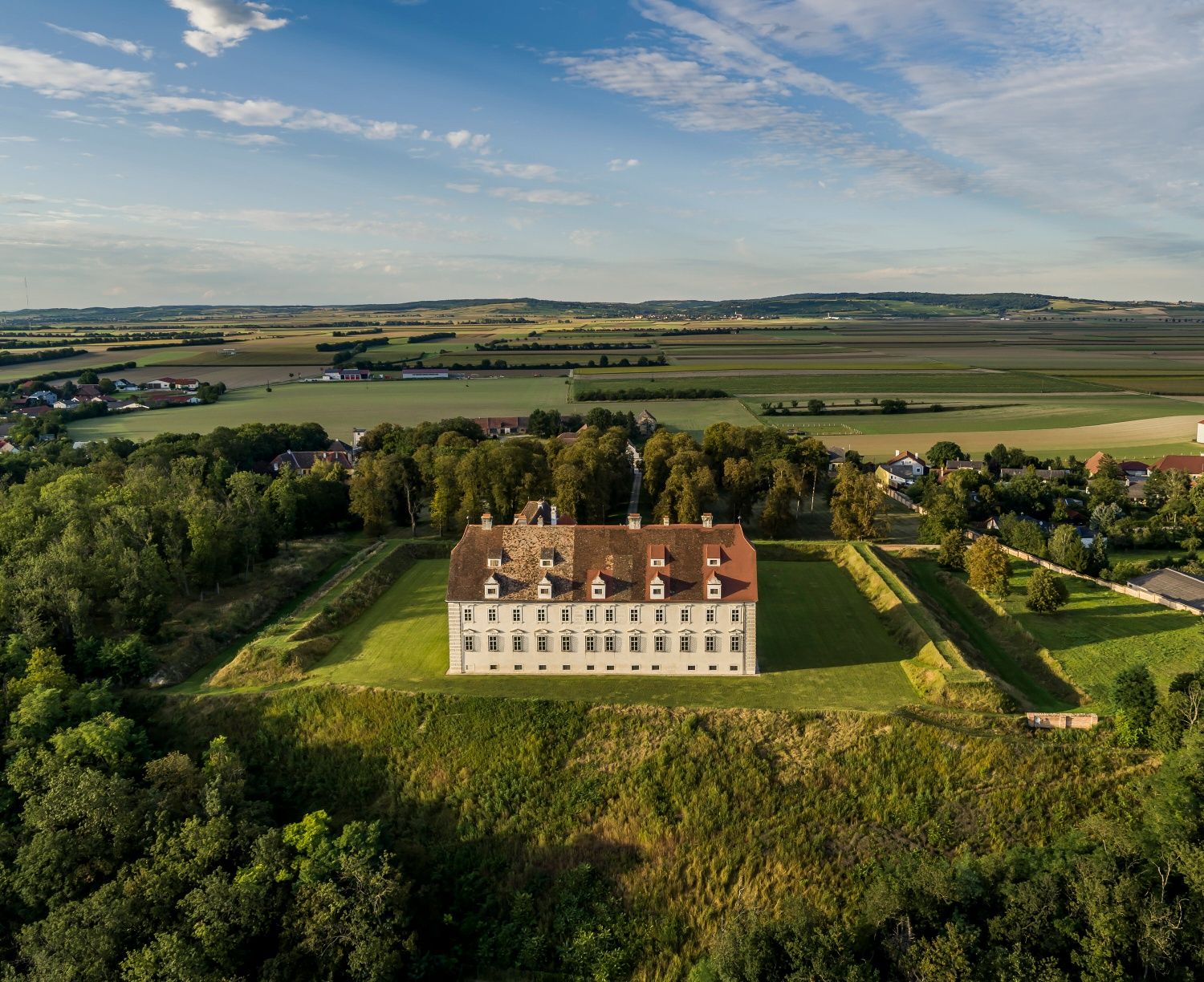 Légi felvétel a Schloss Stetteldorf am Wagramról, zöld vidékkel és mezőkkel körülvéve.