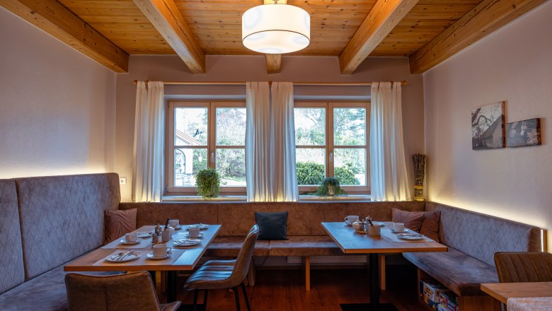 Hangulatos &eacute;tkező fagerend&aacute;s mennyezettel, ablakkal &eacute;s ter&iacute;tett asztallal.