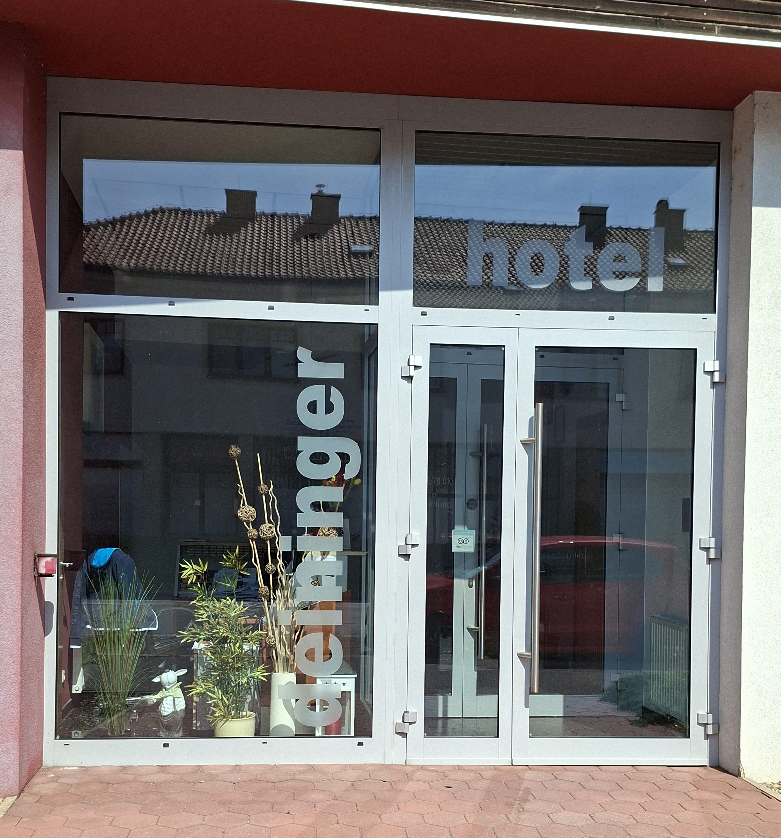 A Hotel Deininger bejárata üvegfronttal és növényekkel.