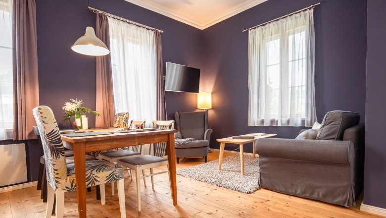 Hangulatos nappali fapadl&oacute;val, &eacute;tkezőasztallal, sz&eacute;kekkel, fotelekkel &eacute;s kanap&eacute;val.