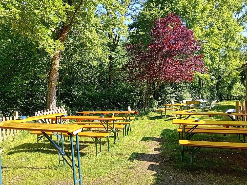 Sörkert üres fapadokkal és asztalokkal a fák alatt.