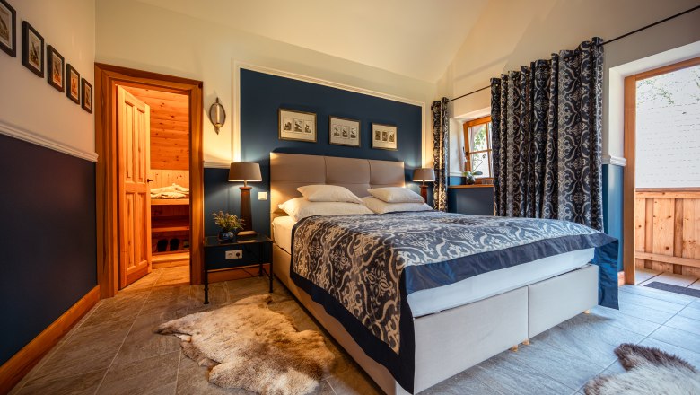 Hangulatos h&aacute;l&oacute;szoba francia&aacute;ggyal, k&eacute;k falakkal &eacute;s fa elemekkel, szauna mellett.