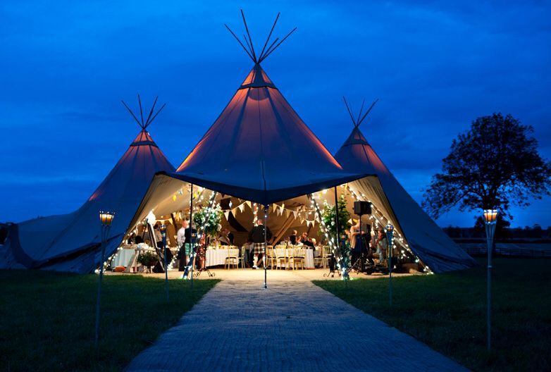 Egy kivilágított tipisátor éjszaka, ünnepi díszítéssel és vendégekkel odabent.