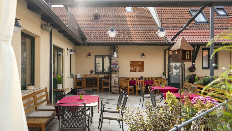 Hangulatos belső udvar &uuml;lőhelyekkel &eacute;s piros ter&iacute;tőkkel.