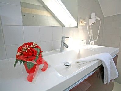 Modern fürdőszoba mosdóval, törölközővel, hajszárítóval és virágköteggel.