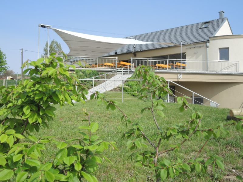 Borkocsma terasszal és napellenzővel, zöld vidékkel körülvéve.