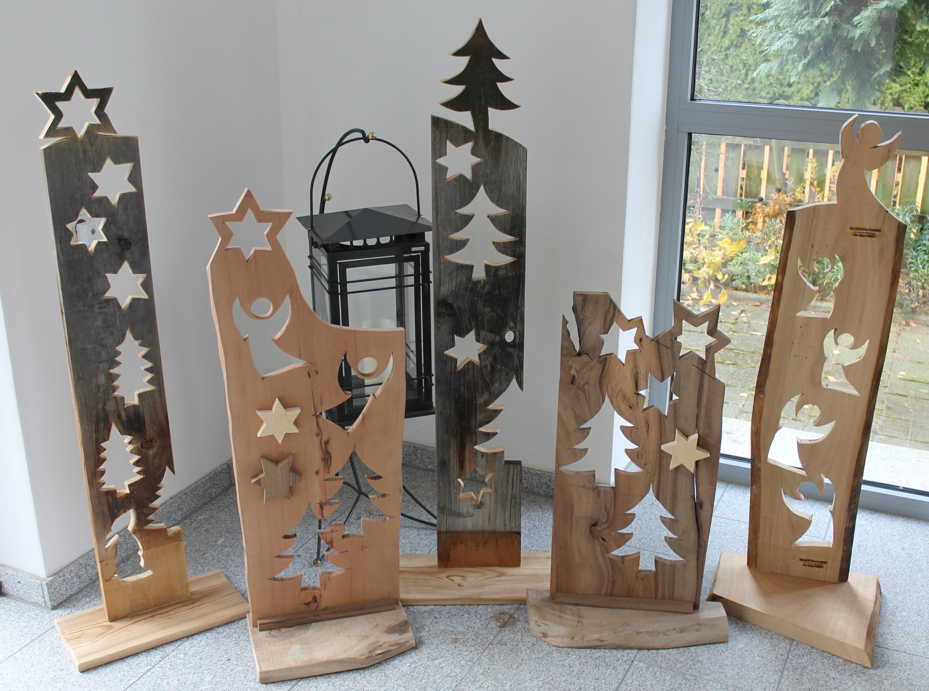 Fadíszek csillagokkal és angyalokkal egy ablak előtt.