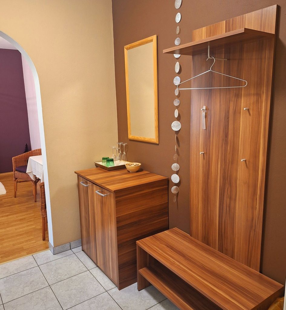 Modern bejárati rész fabútorokkal, tükörrel és dekorációval.