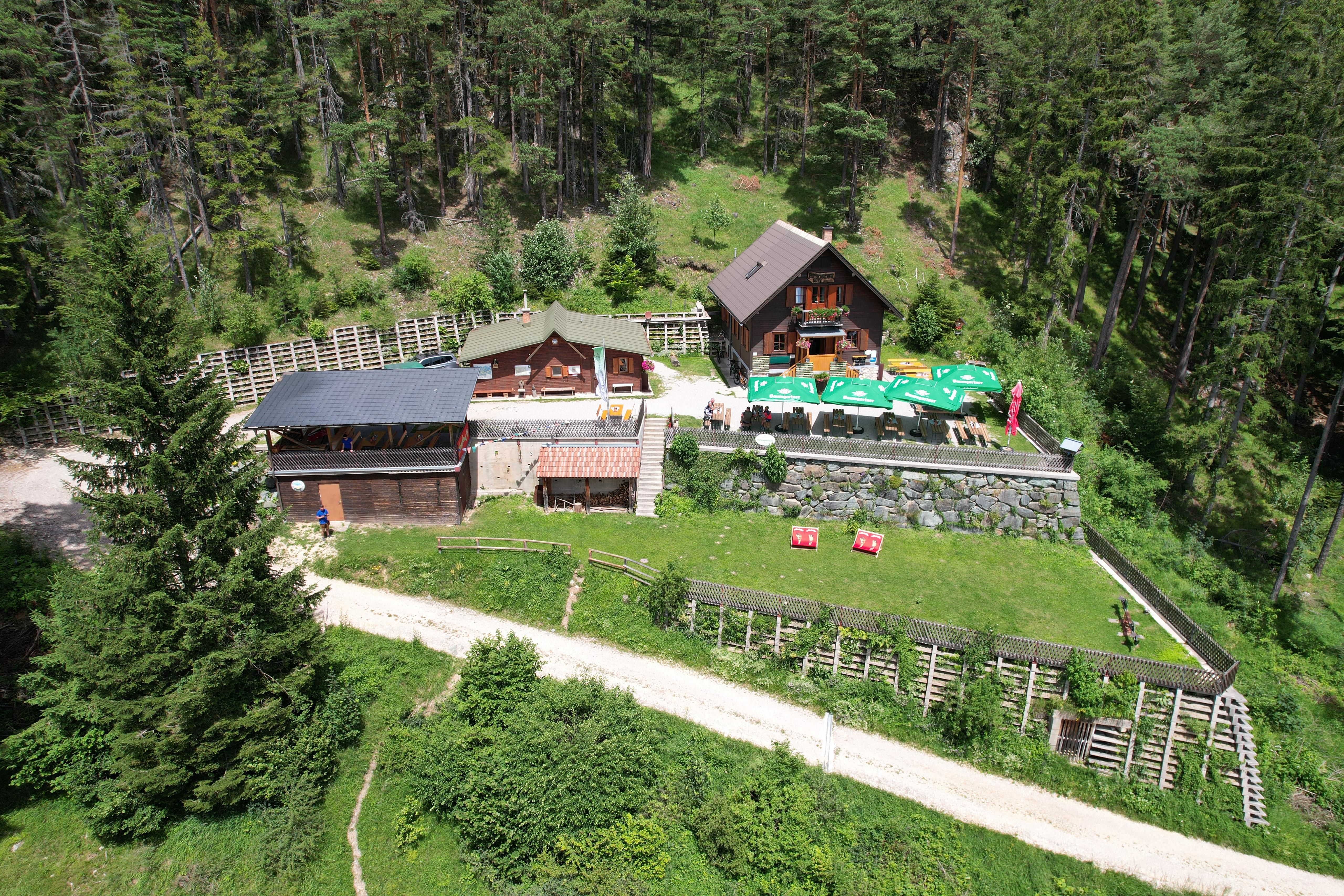 A Potschacherhütte légifelvétele egy erdős területen, a környező fákkal és egy napernyős terasszal.