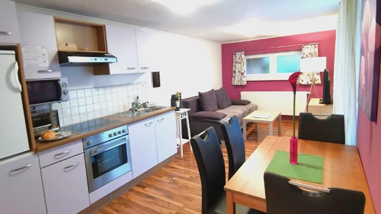 Egy modern lakás belső nézete konyhával, étkezőasztallal és kanapéval.