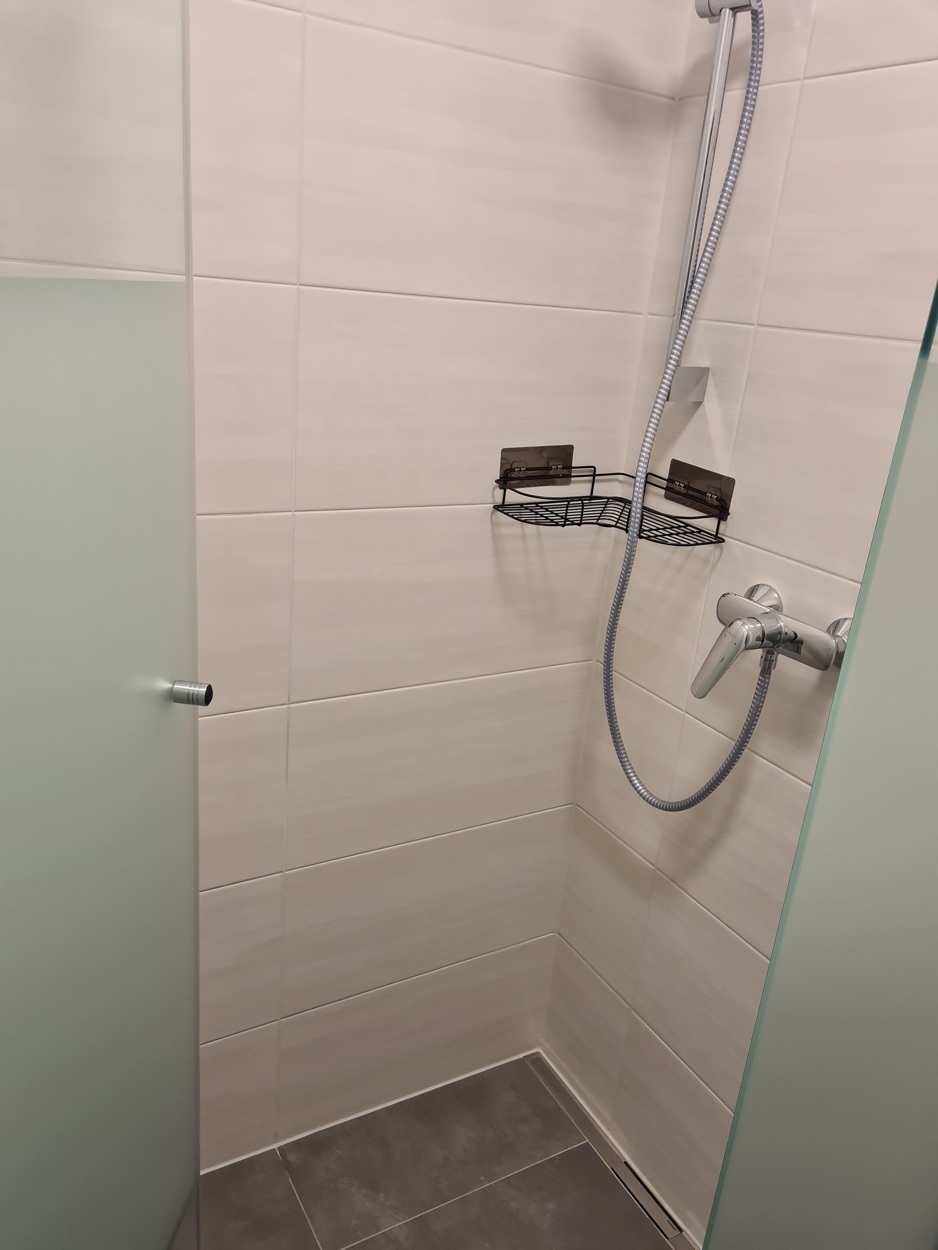 Modern zuhanyzó üvegfallal és zuhanyfejjel.