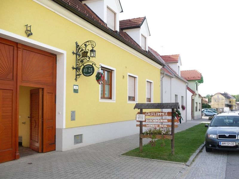 Sárga épület 'Gästezimmer Hagyományos borozó Poys' felirattal és parkoló autóval előtte.