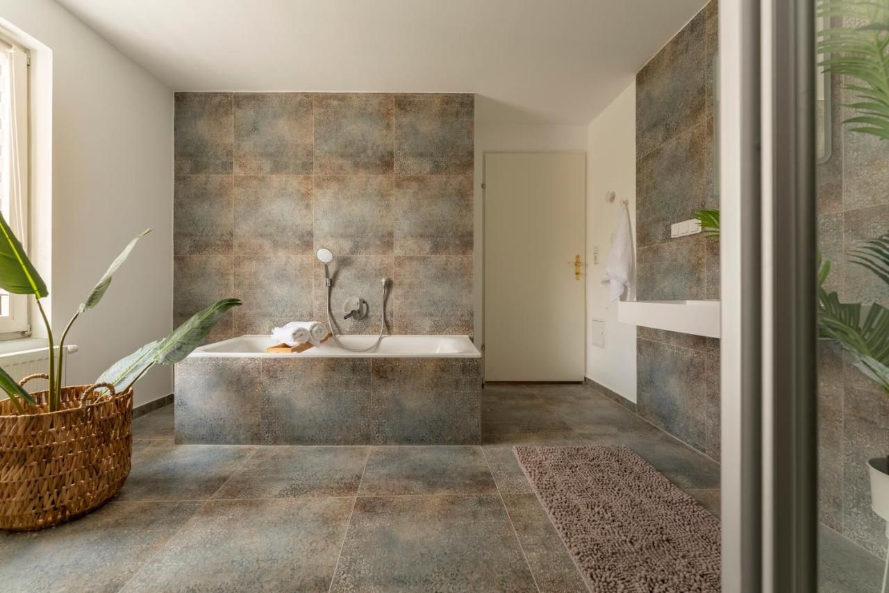 Modern fürdőszoba káddal, növényekkel és törölközővel.