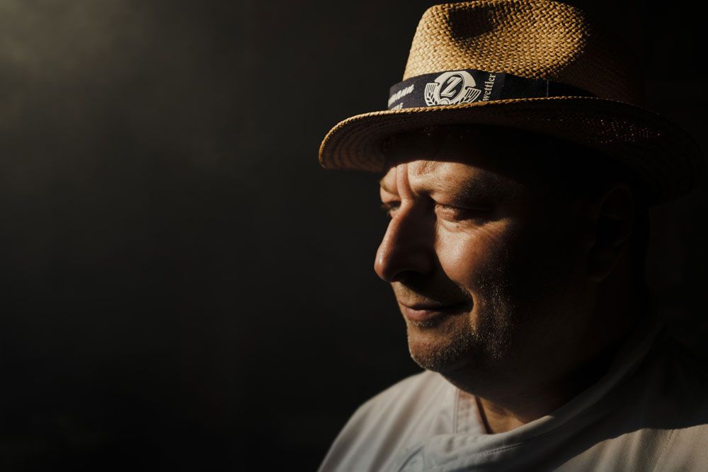 Egy szalmakalapos férfi portréja profilból, árnyékban áll.