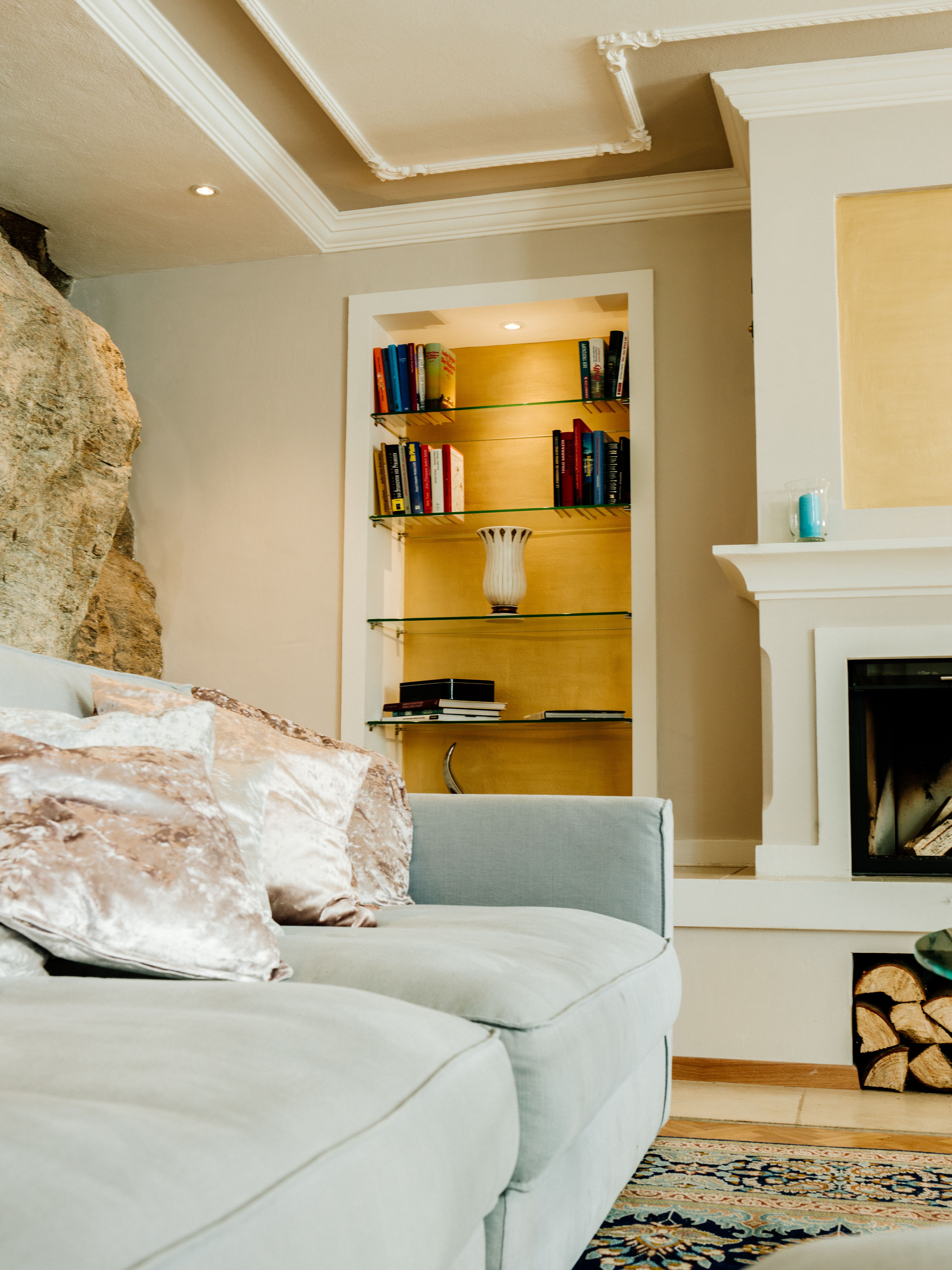 Elegáns nappali szürke kanapéval, könyvespolccal és kandallóval.