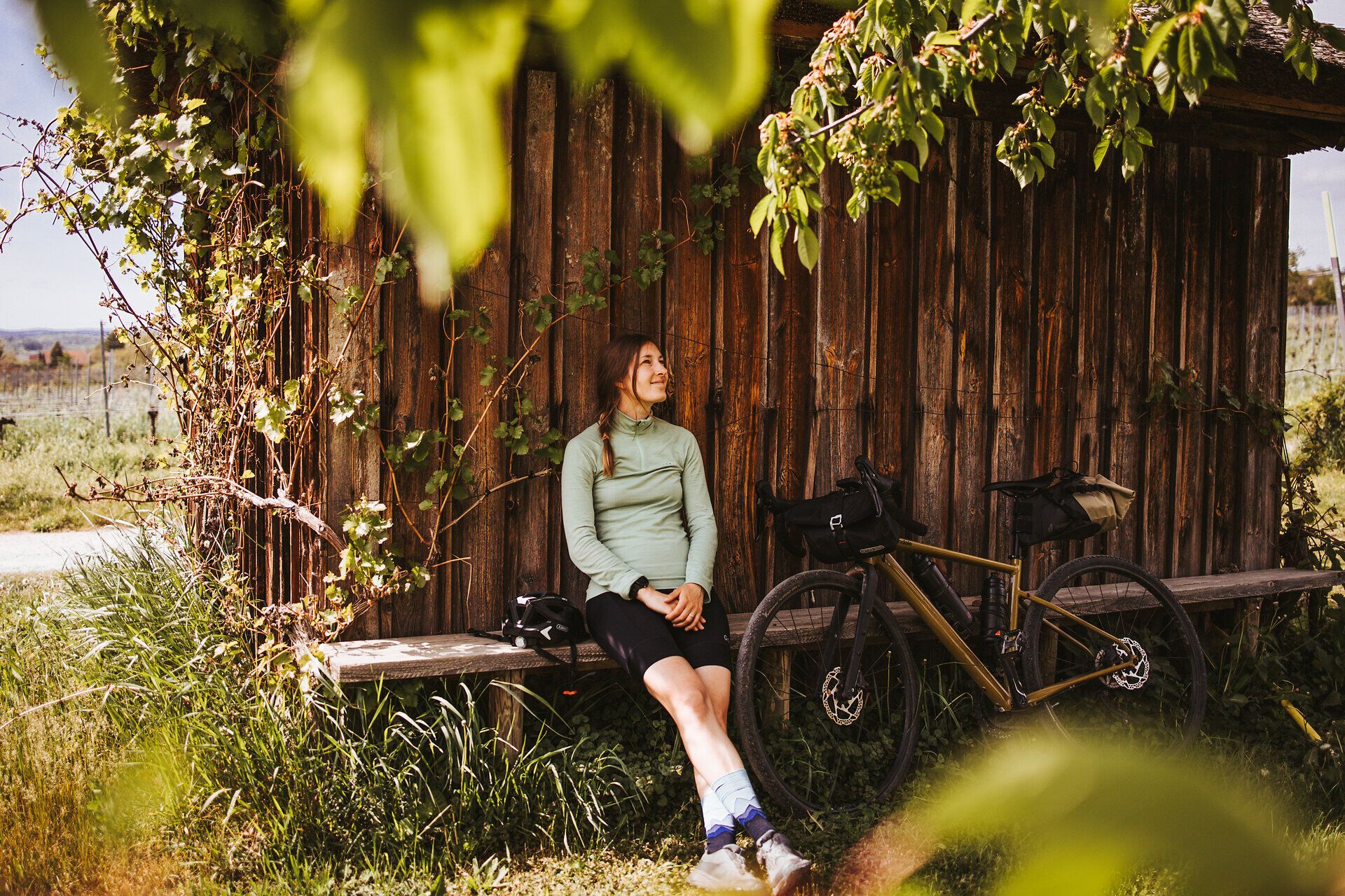 Inmitten der sanften Hügel des Waldviertels genießt eine Radfahrerin eine wohlverdiente Pause. Umgeben von üppigem Grün und der warmen Sonne strahlt die Szene Ruhe und Freiheit aus. Die frische Luft und die malerische Landschaft laden dazu ein, die Schönheit der Natur zu erkunden.