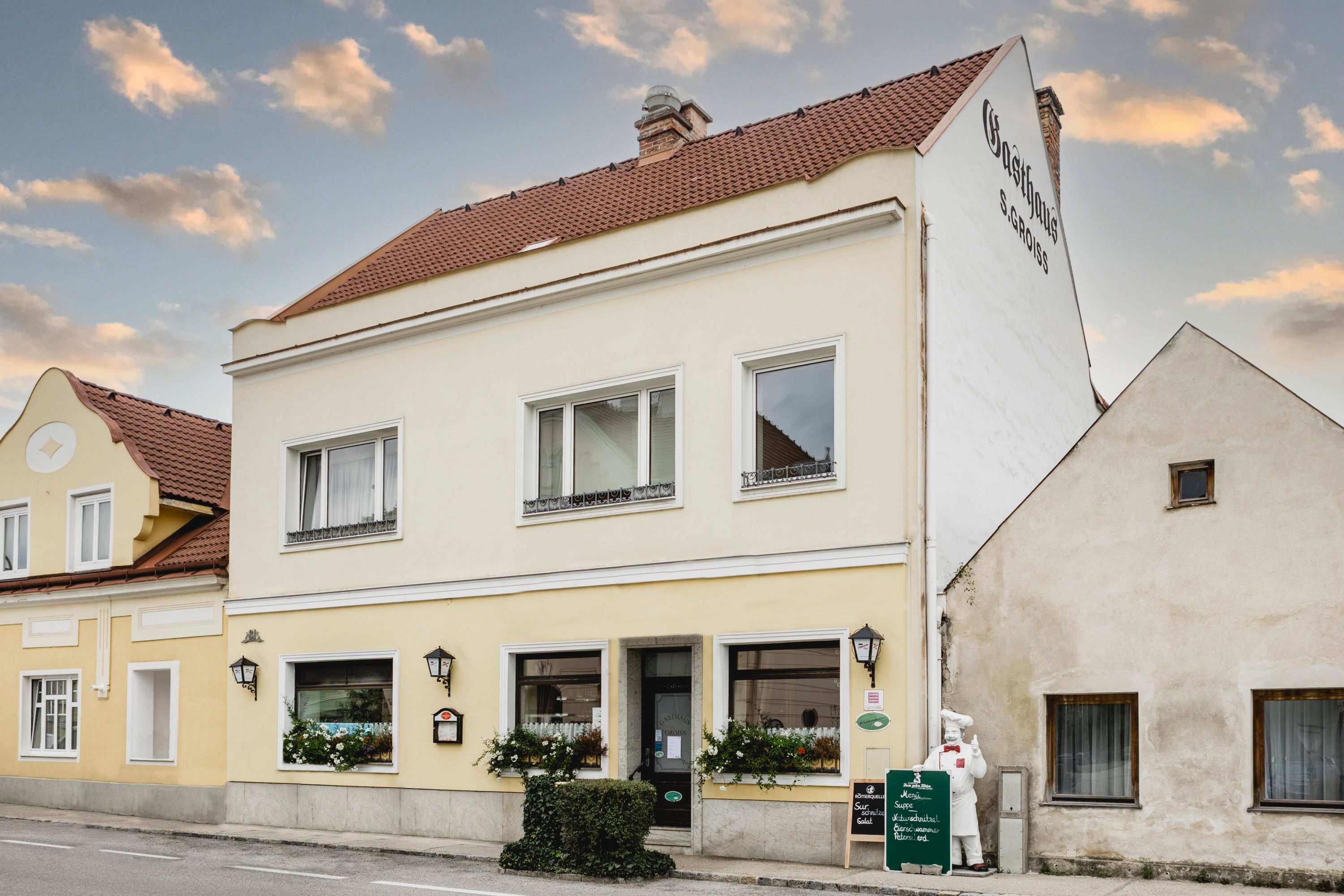 Sárga vendéglő táblákkal és virágokkal Berndorfban.