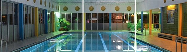 Belső nézet egy megvilágított fedett medence medencével és növényekkel.